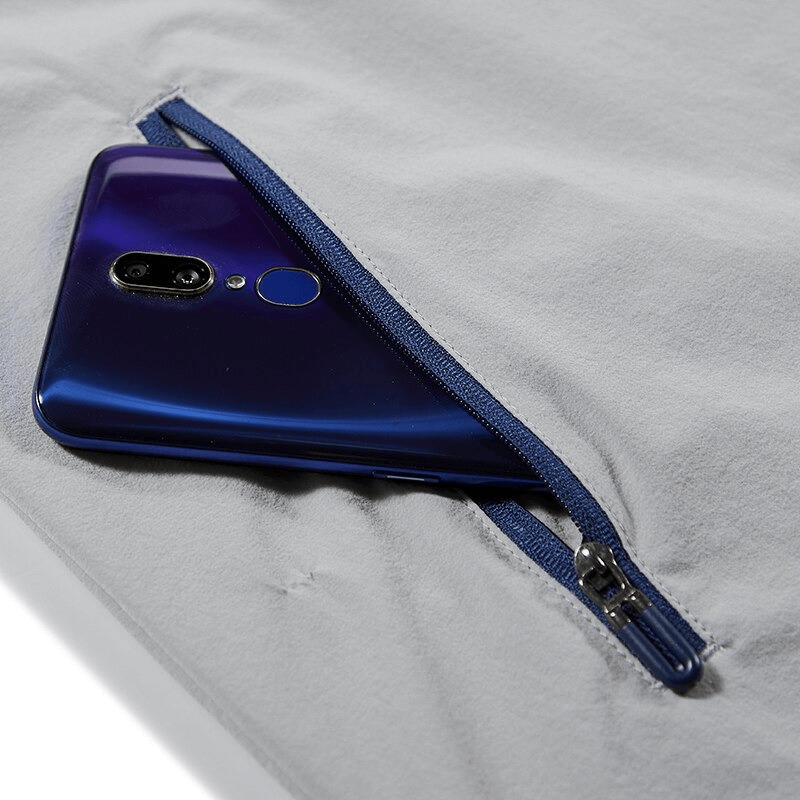 Close-up of a jacket's blue zippered pocket securely holding a smartphone, showcasing its practicality for outdoor adventures.