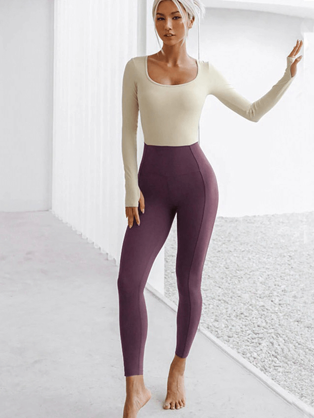 Woman in a stylish fitness jumpsuit doing yoga, wearing a hollow back one-piece patchwork yoga set, perfect for breathability and comfort