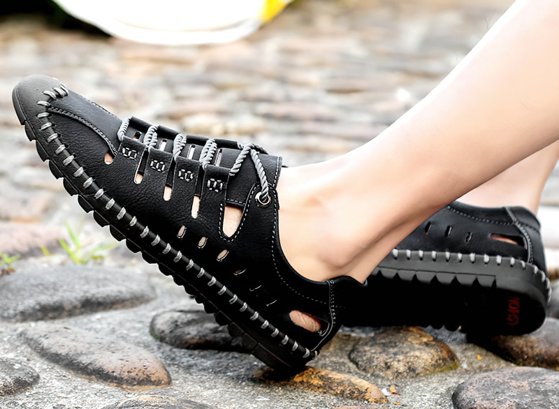 Men's black lace-up leather outdoor water shoes with a durable rubber sole on a cobblestone path.