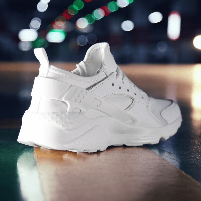 White lace-up mesh elastic running shoe on shiny surface, showcasing breathable design for marathoners.