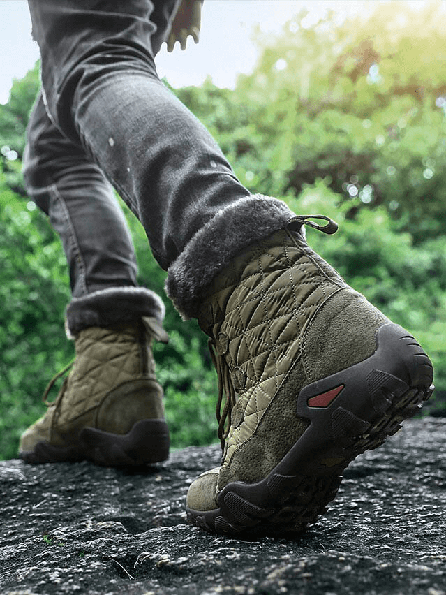 Person wearing lace-up waterproof mid-calf snow boots with fur walking outdoors on rocky surface