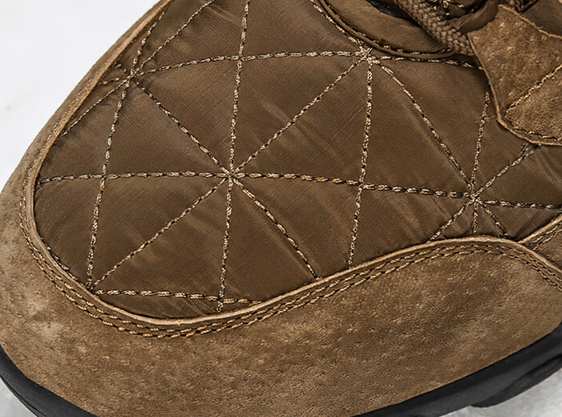 Close-up of a brown lace-up waterproof snow boot showing quilted cotton fabric and non-slip rubber sole.