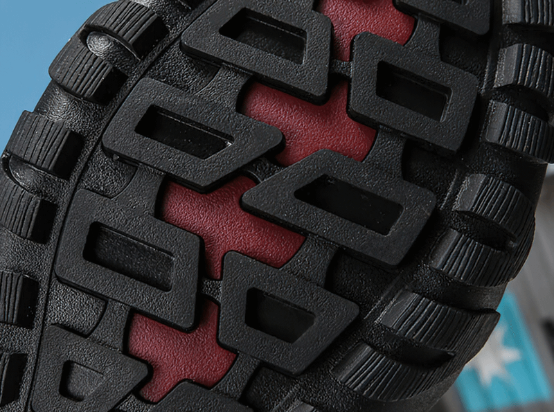 Close-up of non-slip sole on black and red snow boot, emphasizing grip and traction for winter weather.