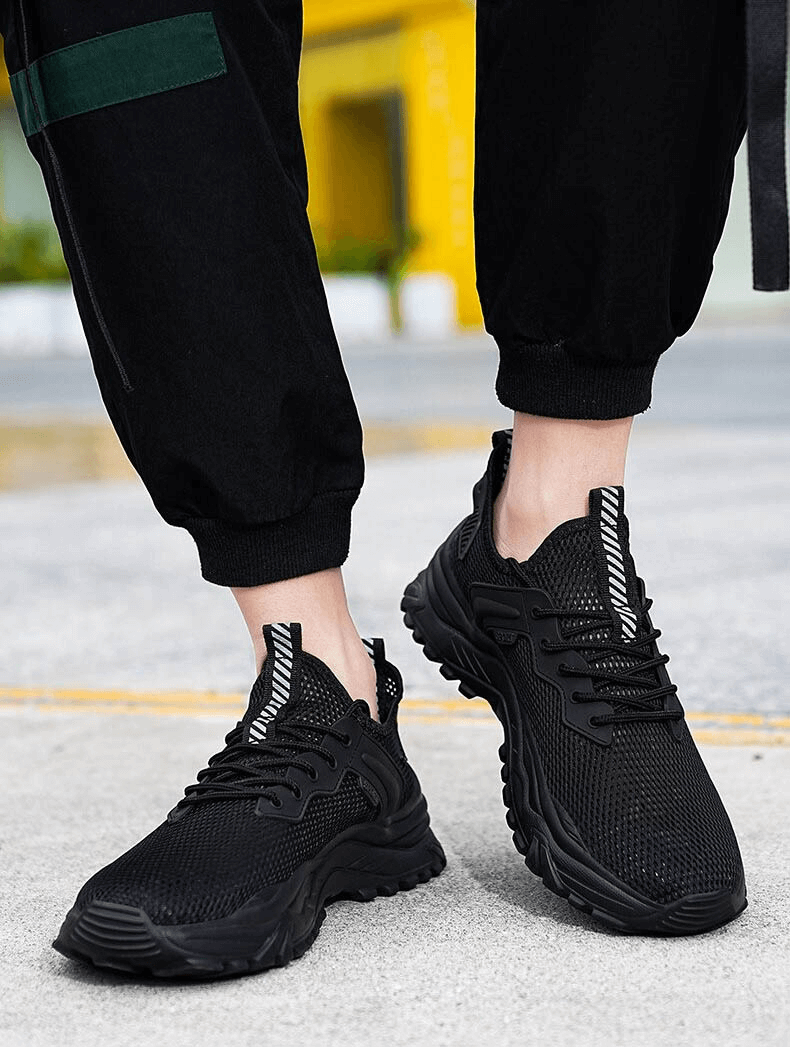 Black breathable sports sneakers with cushioning and lace-up design on a street background, perfect for male athletes.