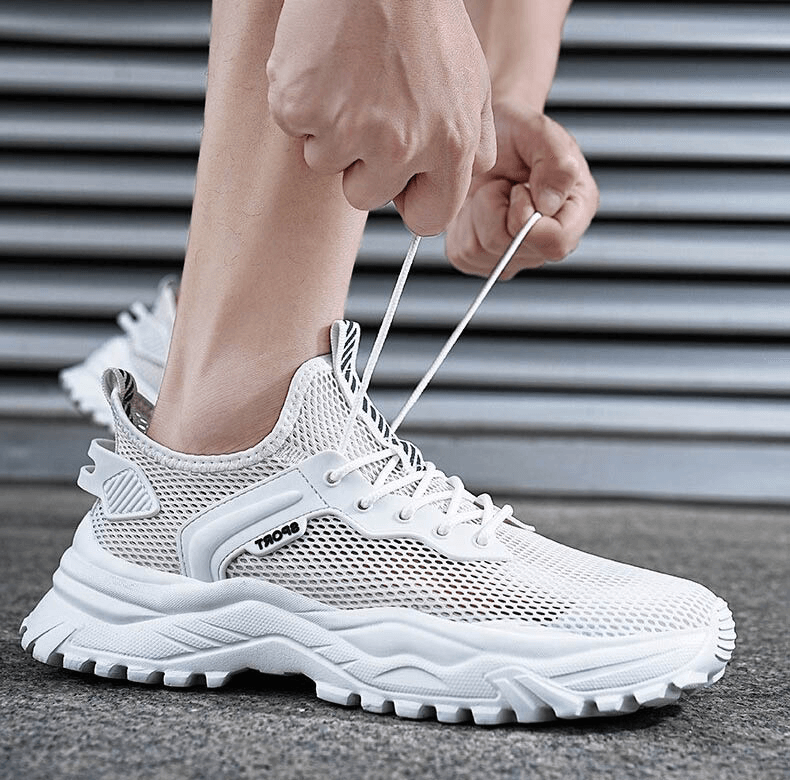 Person tying white breathable running shoes with cushioning, highlighting lace-up feature and mesh design for comfort and performance