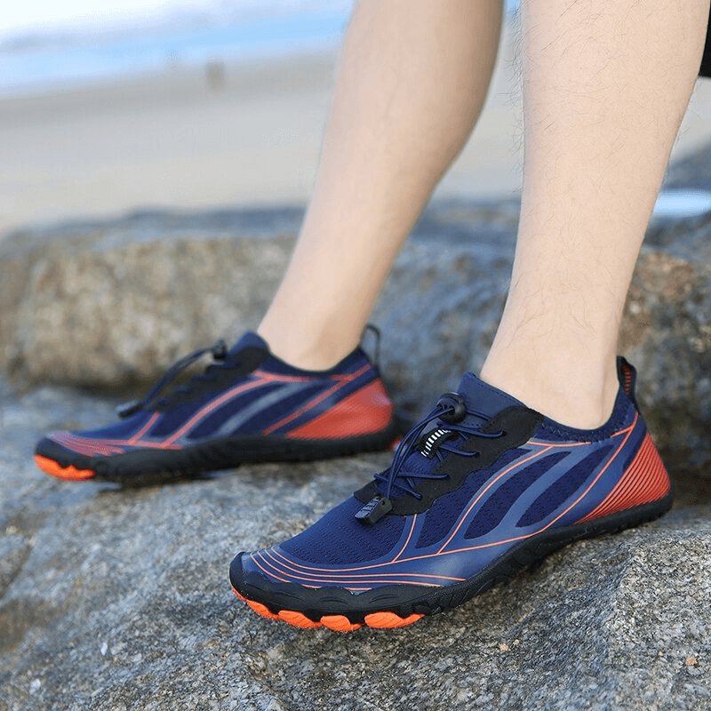 Person wearing light soft water shoes with elastic lacing on a rocky beach; breathable sneakers offering traction and comfort.