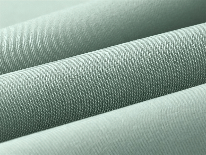 Close-up of high-quality, breathable nylon and spandex fabric in light green, used for sweatpants with sweat-wicking properties.