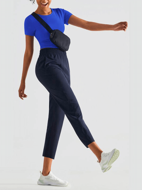 Woman wearing lightweight high waist fitness workout sweatpants with pockets, paired with a blue top and sneakers.