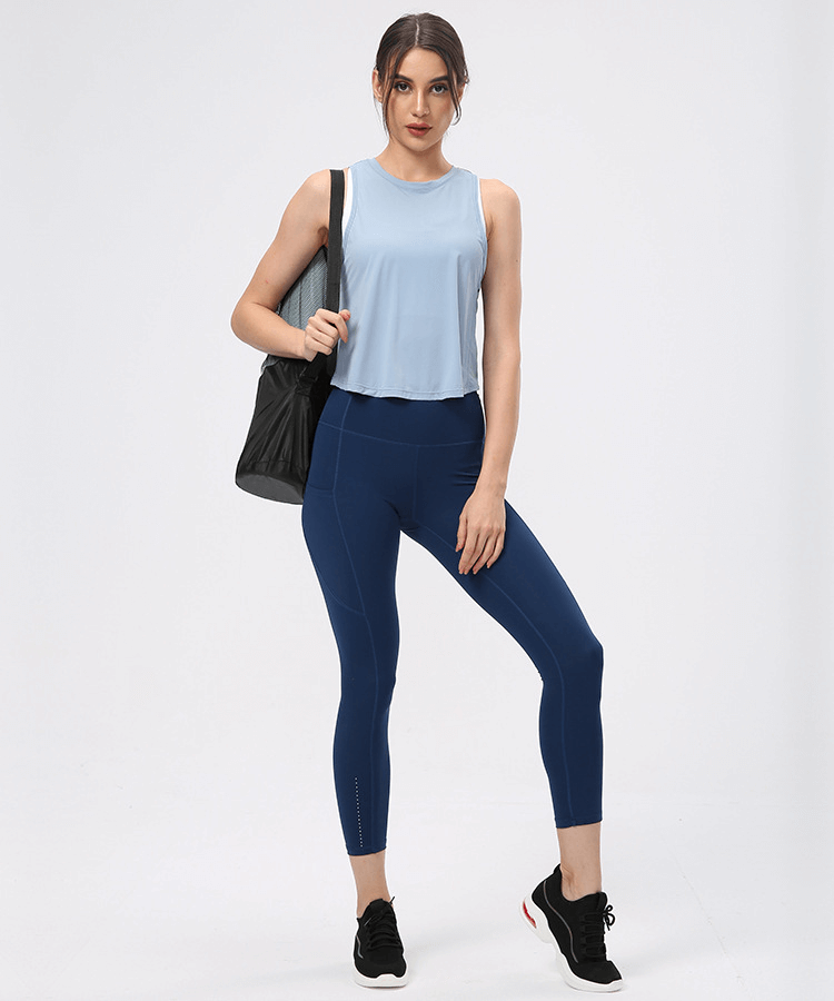 Woman wearing lightweight quick-dry sleeveless t-shirt with mesh back, navy leggings, and sneakers, ideal for exercise or yoga.