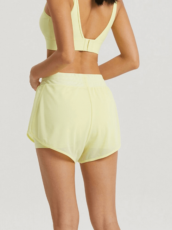 Woman wearing yellow lightweight quick-drying sports shorts for training, showcasing back view with tank top. Ideal for fitness and yoga.
