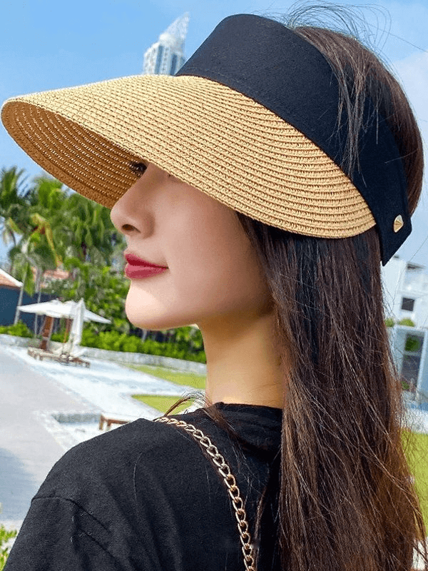 Woman wearing a stylish straw summer hat with an adjustable fastener, perfect for outdoor activities and sun protection.