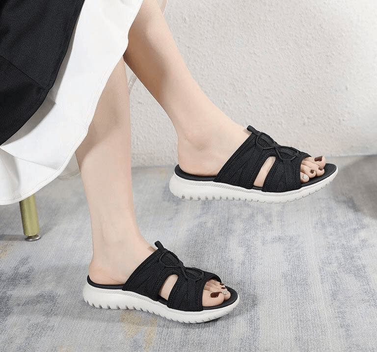Woman wearing black lightweight waterproof athletic flat slippers with white soles, perfect for active lifestyle, SKU SF0977.