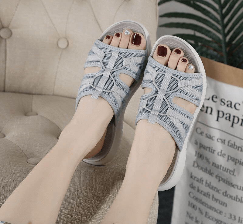 Woman wearing lightweight waterproof athletic slippers resting on beige armchair.