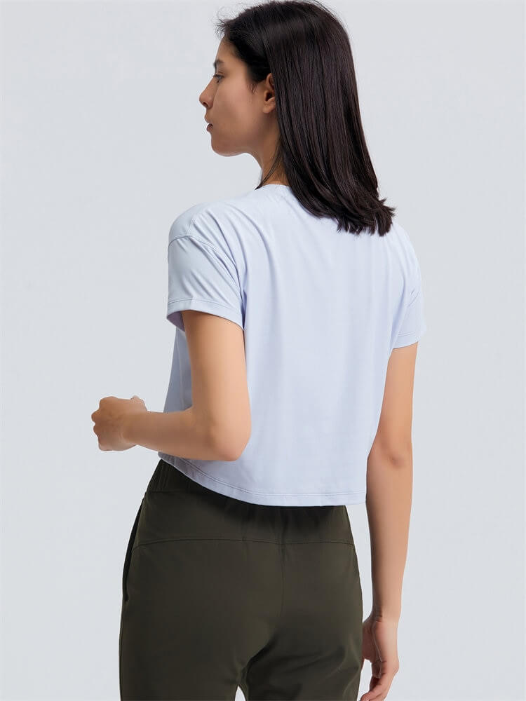 Woman wearing light blue loose-fit crop workout t-shirt, featuring short sleeves, ideal for yoga.