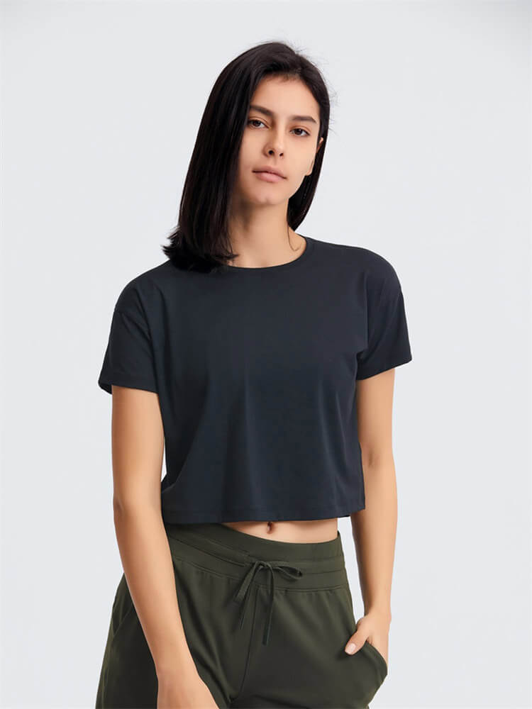 Woman wearing a solid black loose fit workout crop t-shirt, perfect for yoga with short sleeves and comfortable design.