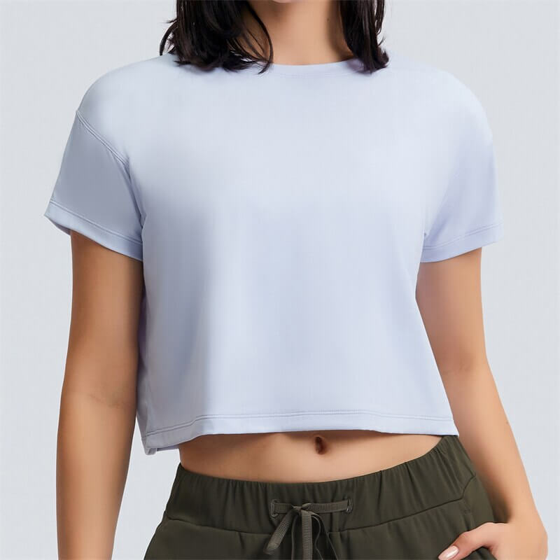 Woman wearing a loose fit solid crop t-shirt, perfect for yoga, with short sleeves and superior breathability.