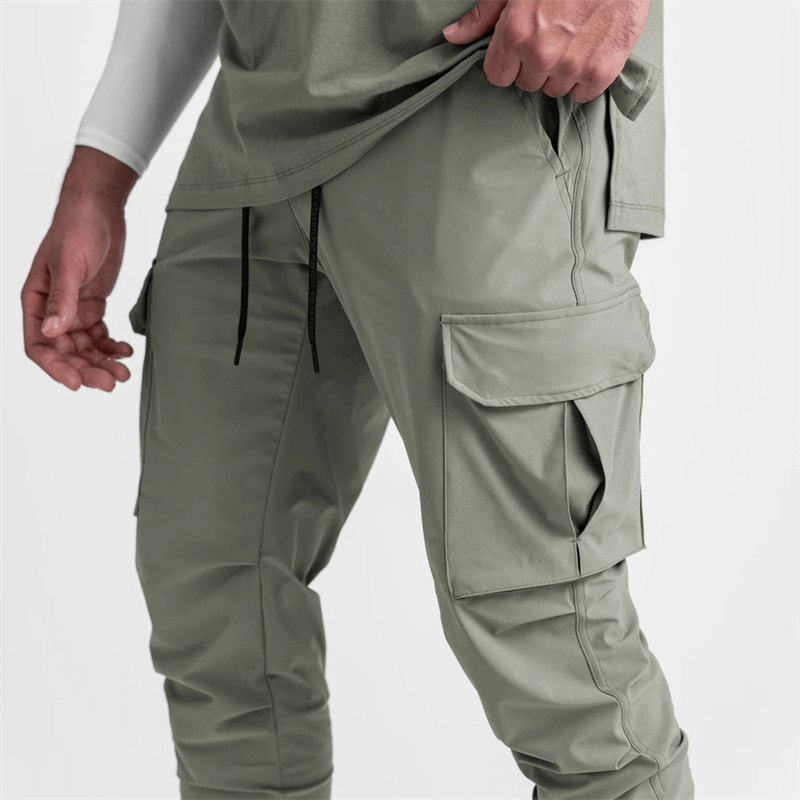 Man wearing loose slim elastic joggers with wide cuffs and drawstring closure, ideal for running and exercise, in gray color.
