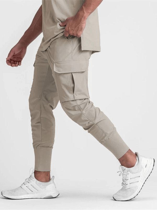 Man wearing beige loose slim elastic joggers with wide cuffs, featuring a comfortable design for exercise and casual wear.