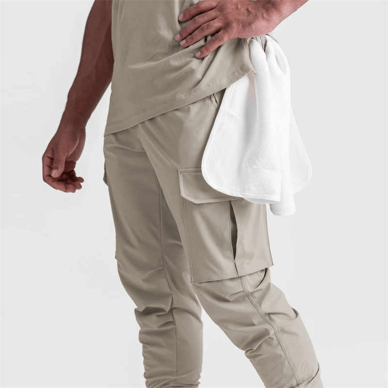 Man wearing loose slim elastic joggers pants for men with wide cuffs, holding a white towel.