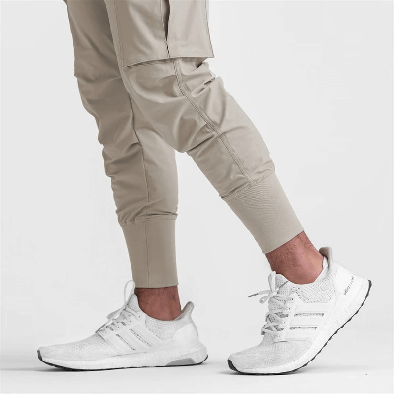 Men's beige joggers with wide cuffs paired with white sneakers, ideal for running and exercise in lightweight, breathable fabric. SF1141