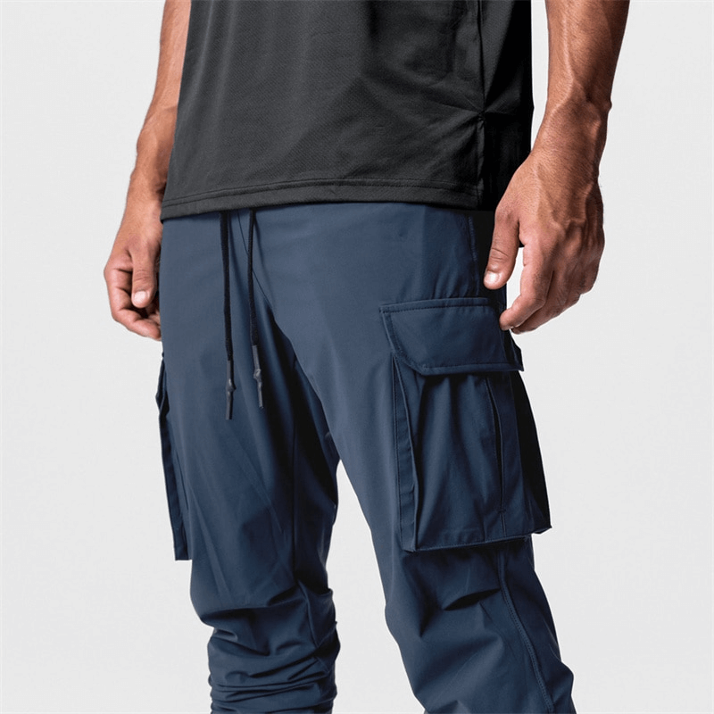 Men's loose slim elastic joggers with wide cuffs in navy, featuring drawstring closure and functional cargo pockets.