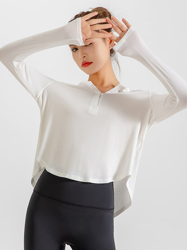 Woman wearing a loose white V-neck top with thumbholes, perfect for yoga and running, paired with black leggings.