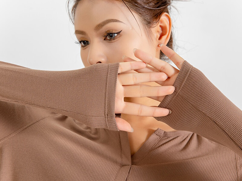 Woman wearing a loose v-neck top with long sleeves in natural color, showcasing the quick dry fabric. Ideal for yoga and running.