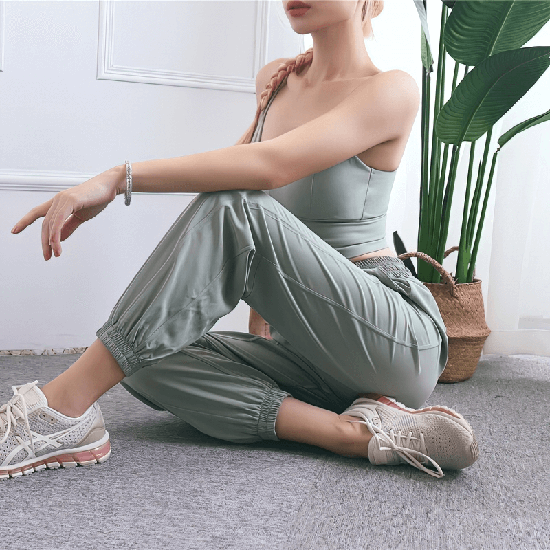 Loose women's high-waisted yoga pants in green, ideal for comfort and style, shown with sneakers in a casual home setting.
