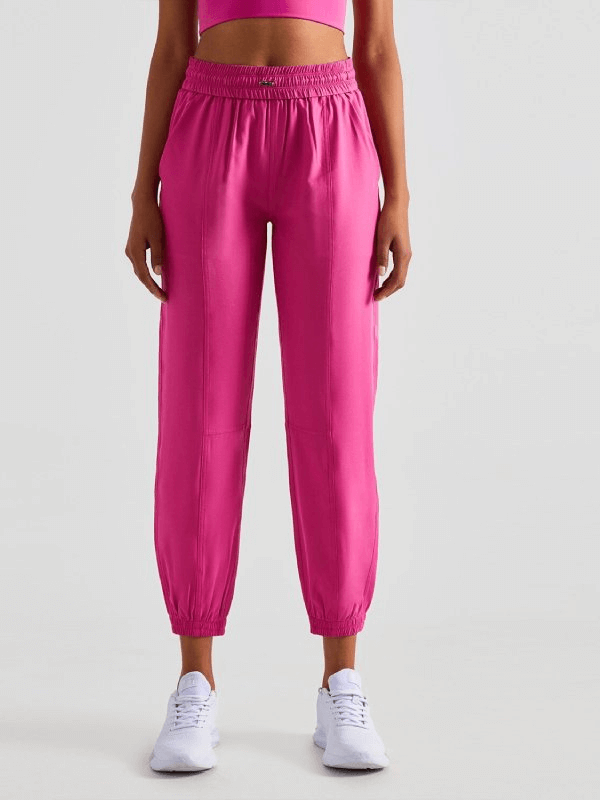 Model wearing pink loose high-waisted yoga pants with drawstring, perfect for comfortable training and casual wear.