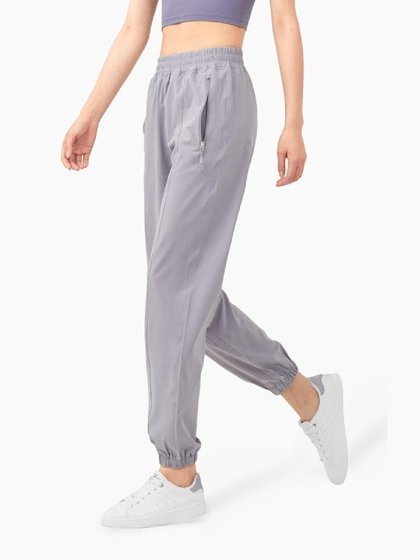 Model wearing loose high-waisted yoga pants in gray, perfect for comfort and style with a drawstring closure and elastic cuffs.