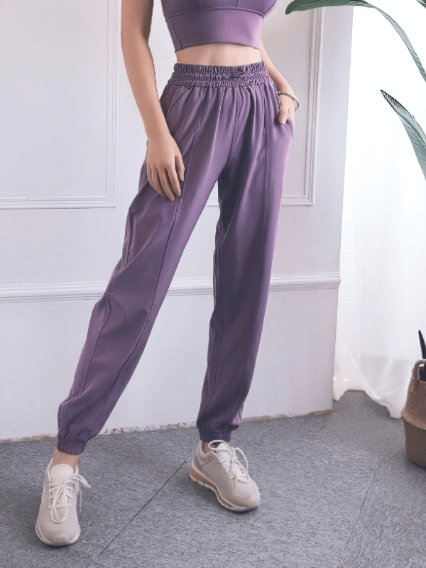 Woman wearing loose high-waisted purple yoga training pants with drawstring, perfect for comfortable all-day wear and leisure activities.