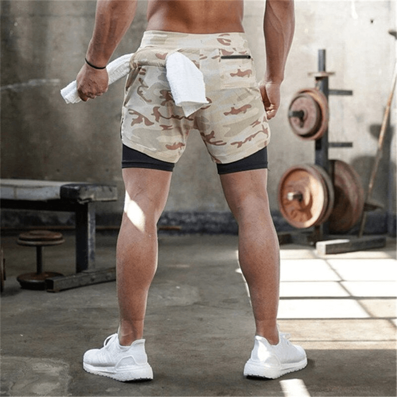 Back view of male in gym wearing camo double-deck running shorts with built-in pockets, showcasing athletic build and comfort style.