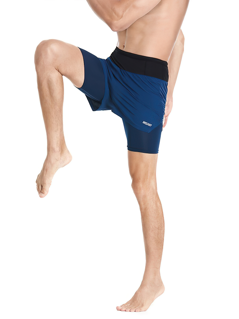 Male in blue double-layer high waist shorts for running, knee raised, showcasing flexibility.