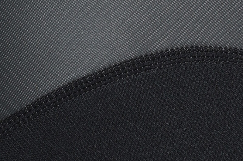 Close-up of black and gray neoprene fabric on men's short sleeve wetsuit, highlighting stitching detail and texture.