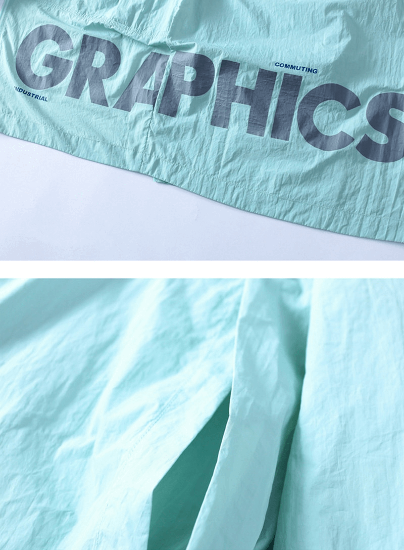 Close-up of light blue windbreaker jacket with bold 'Graphics' text, showing fabric texture and pocket detail.