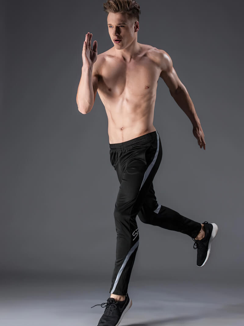 Male model wearing SF0446 elastic waist workout trousers, running pose, showcasing comfort and athletic style, black with stripe design.
