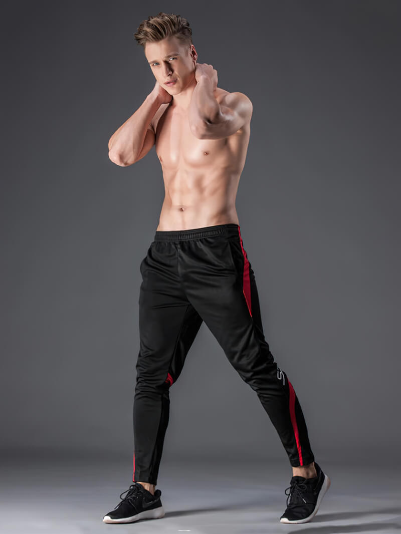 Male model wearing black and red sports elastic waist trousers for workout performance.