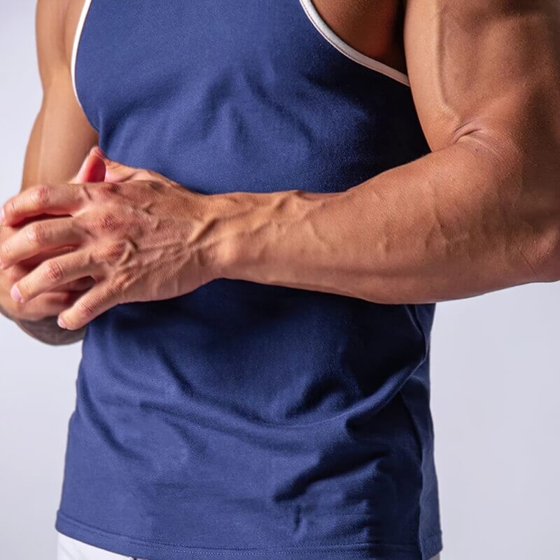Muscular man wearing a navy cotton tank top, showcasing comfort and flexibility for bodybuilding workouts.