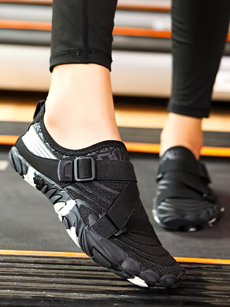 Person wearing black breathable elastic water shoes for surfing, ideal for water sports and outdoor activities, on treadmill.