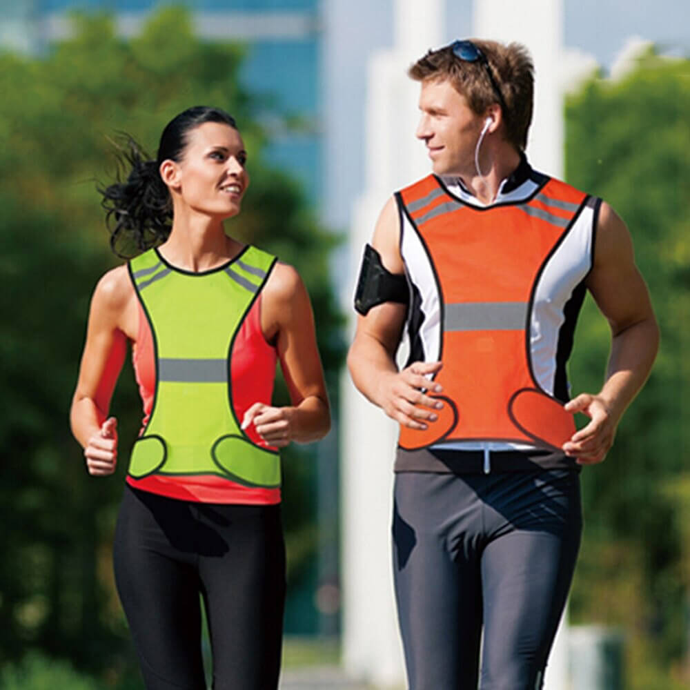 Man and woman jogging wearing reflective vests for high visibility at night, ensuring safety and style in low light conditions.