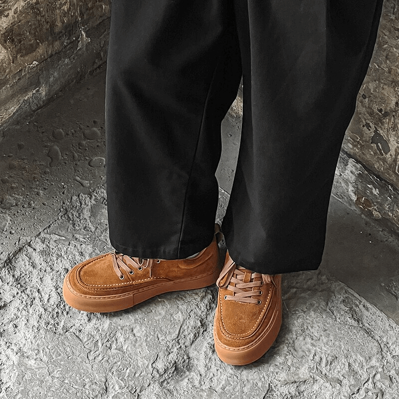 Men's breathable leather casual shoes SF0973 with black pants, showcasing stylish sneakers on a stone surface.