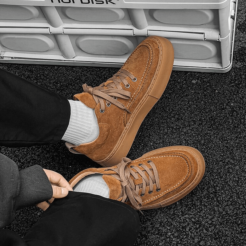 Alt Tag: Men's breathable leather casual shoes in brown, showcasing stylish design and comfort, worn by a person sitting on a textured floor.