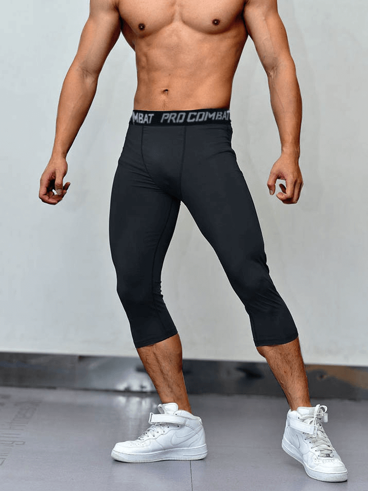 Man wearing black men's breathable compression Capri pants for gym with white sneakers.