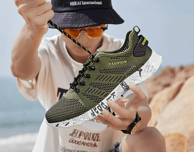 Man holding green men's casual lace-up mesh sneakers with soft outsole, showcasing fashion-forward design and comfort features.