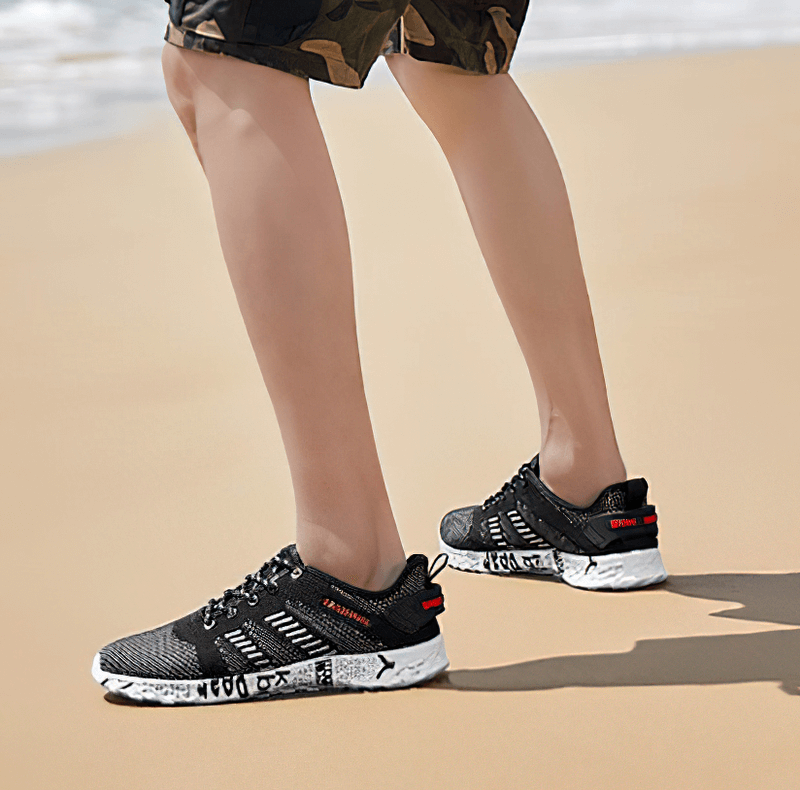 Man wearing Men's Casual Lace-up Mesh Sneakers SF0805 walking on sandy beach, stylish comfort with soft outsole and geometric design.