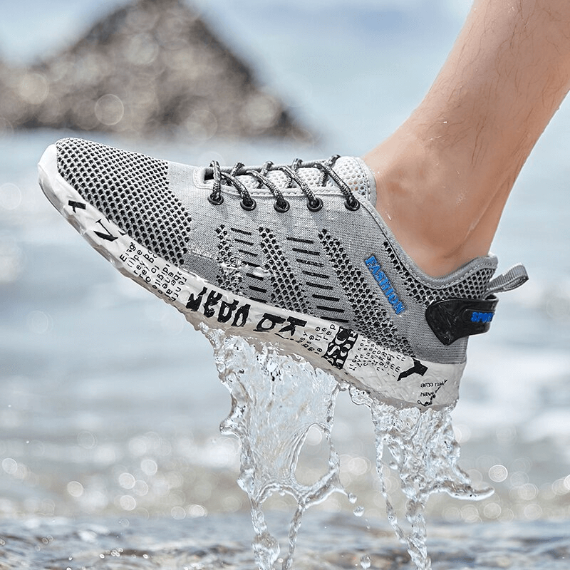 Man wearing stylish mesh sneakers with lace-up design, stepping through water, showcasing soft outsole and breathable material.