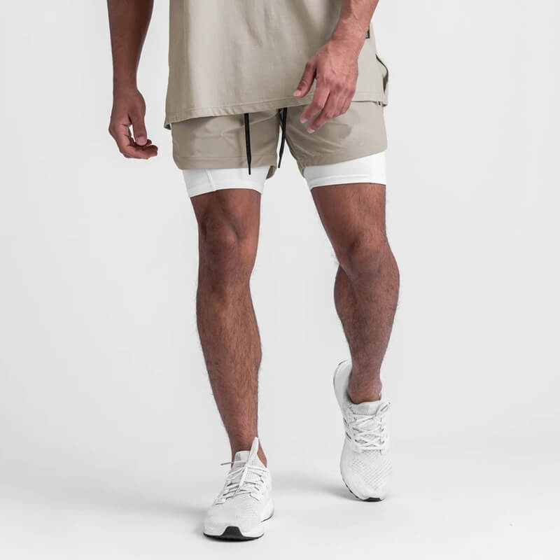 Man wearing beige men's double-layer sports running shorts with pockets, showcasing comfort and style for active lifestyle.