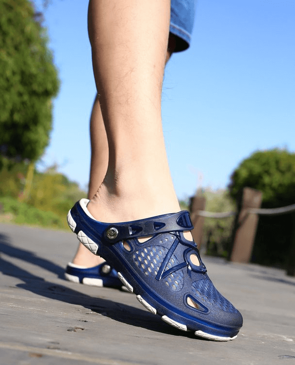 Blue breathable men's beach flip flops with locking strap and open heel design on a sunny pathway.