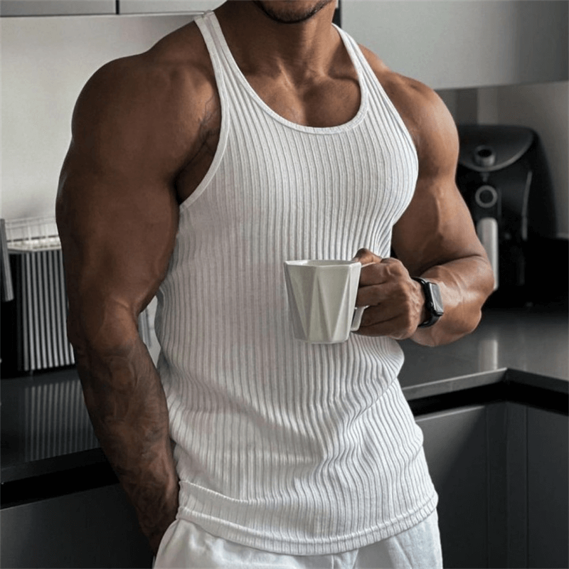 Men's pure white ribbed tank top, sleeveless design perfect for fitness, shown on a muscular man holding a coffee cup in a kitchen.
