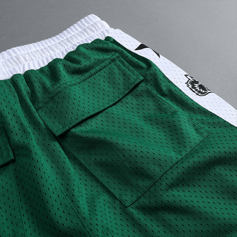 Close-up of green men's quick-drying basketball shorts with pockets, showing elastic waistband and breathable fabric.